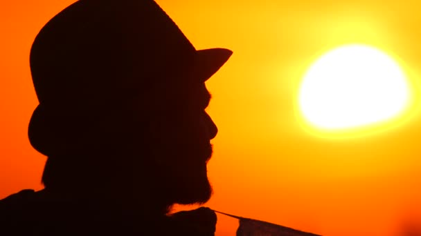 Guy Puts Medical Mask on His Face on Sunny Morning. Silhouette a Young Man Putting On a Protective Facemask on the Beautiful Sunset, Sunrise Background. New Day. New lifestyle. Sunrise View. Covid 19 — Stock Video