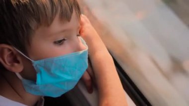 Çocuk, Coronavirus, Covid-19 pandemik sırasında tren penceresinden hızlı koşu görüntüsüne bakıyor. Maskeli Çocuk Gidiyor, Trenle Yolculuk Pencereden Dışarı Bakıyor. Okul tatilinden döndüm.