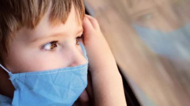 Trenle Seyahat Eden Çocuk, Yolun Nasıl Hızlı Hareket Ettiğini İzliyor. Genç Yolcunun Mavi Maskeli Yüzünde Güneş Işığı. Salgın Covid 19, Coronavirus. Maskeli çocuk bardakta yansıyor. Kapat.