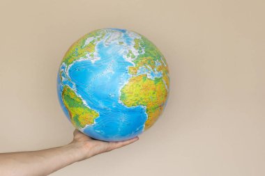 Elini bej renkli bir arka plan üzerinde renkli Küre tutar. izole