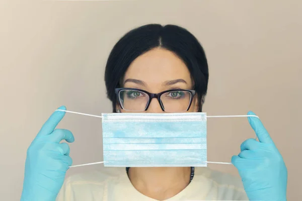 Doktor Şevval özçelik Güzellik esmer bir maske mavi eldiven koyar. bej renkli arka plan. izole