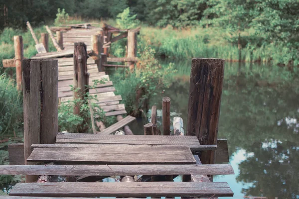 a wooden crumbling wooden bridge across the river. blurred backg