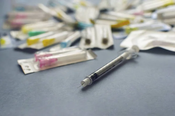 syringe with needle close-up. sealed needles blurred in the background