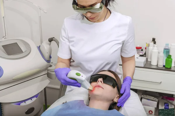 美容师医生对女孩的脸上的皮肤进行激光手术 — 图库照片