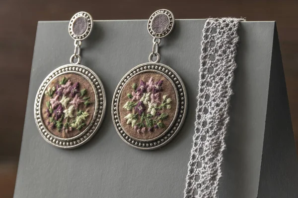 El yapımı küpe gri bir stand üzerinde yuvarlak bir şekil ile işlemeli. moda yakın çekim.