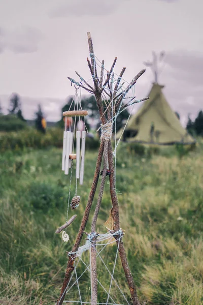 wind bell on a pine branch. Tipi in the background is blurry
