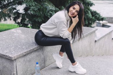 parkta bir parapet üzerinde oturan güzel mutlu kız. yürüdükten sonra dinlenmek