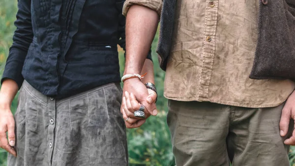 Bir erkek ve bir kız aşık keten giysiler içinde el ele tutuşuyorlar.