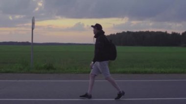 Gezgin sabahın erken saatlerinde şafakta boş bir yolda gider