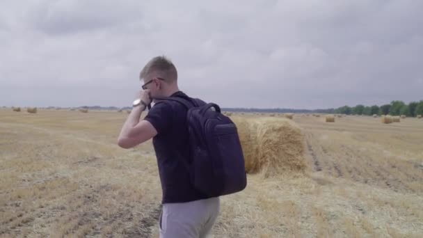 Der Reisende ist auf dem Feld zwischen Heuballen — Stockvideo