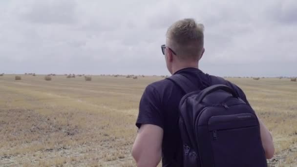 Путешественник на поле среди тюков сена — стоковое видео