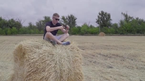 Podróżny ma selfie, siedząc na bele siana — Wideo stockowe