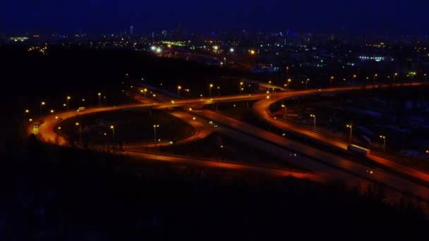 Aerial view of a large illuminated road junction at night full of cars and trucks. — Stock Video