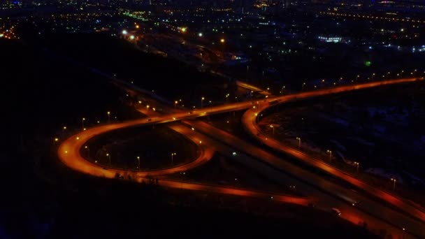 Letecký pohled na velký osvětlený silniční uzel v noci plný aut a nákladních aut. — Stock video