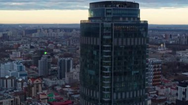 Şafakta gökdelenin havadan görünümü. Drone binanın yakınında uçar ve şehrin bir panoramasını açar..