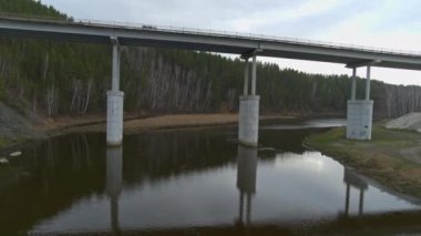 Bir yol köprüsünün altında suyun üzerinde uçarken