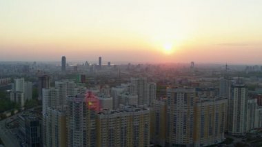 Şehrin üzerindeki parlak turuncu gün batımının havadan görüntüsü.