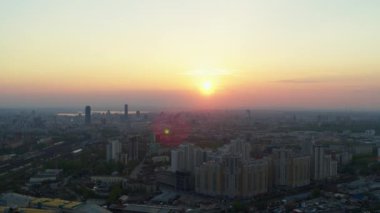 Şehrin üzerindeki parlak turuncu gün batımının havadan görüntüsü.