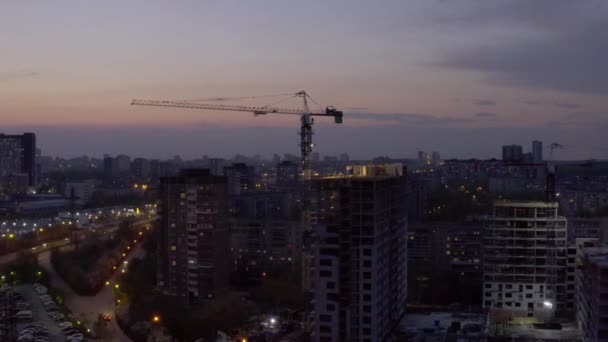 Letecký pohled na stavební jeřáb a stavbu budovy za soumraku. — Stock video
