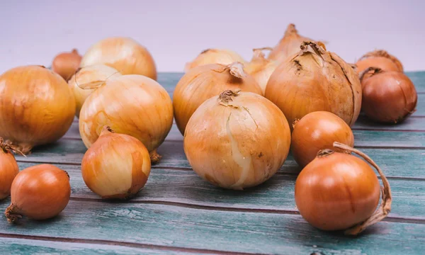 Fresh onion bulbs on wooden background. Vegetables for a healthy diet. Bulb onion is rich in vitamins, useful spring. Onion peel on a wooden background. ingredient for a healthy salad