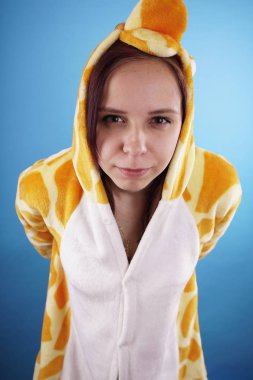 kız bir parlak çocuk pijama bir zürafa şeklinde. duygusal bir öğrenci portresi. Çocuk animatör sunumunu kostüm. Kedinin pençeleri şeklinde terlik.         