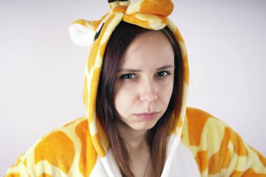 kız bir parlak çocuk pijama bir zürafa şeklinde. duygusal bir öğrenci portresi. Çocuk animatör sunumunu kostüm. Kedinin pençeleri şeklinde terlik.         