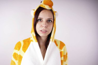 kız bir parlak çocuk pijama bir zürafa şeklinde. duygusal bir öğrenci portresi. Çocuk animatör sunumunu kostüm. Kedinin pençeleri şeklinde terlik.         