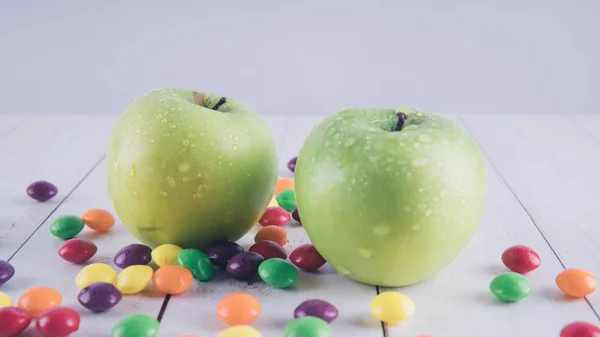 Äpfel Und Bonbons Auf Einem Weißen Holztisch Schädliche Und Gesunde — Stockfoto
