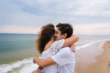 Mutlu çift sahilde ya da okyanusta geziniyor. Sahilde yürüyen aşk çifti.