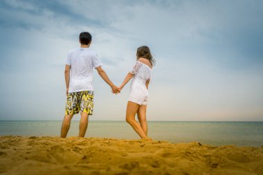 Mutlu çift sahilde ya da okyanusta geziniyor. Sahilde yürüyen aşk çifti.