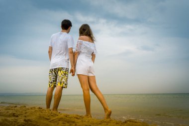 Mutlu çift sahilde ya da okyanusta geziniyor. Sahilde yürüyen aşk çifti.