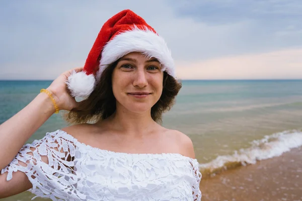 Mutlu Kız Deniz Plaj Üzerinde Noel Baba Şapkalı Gülümseyerek Poz — Stok fotoğraf