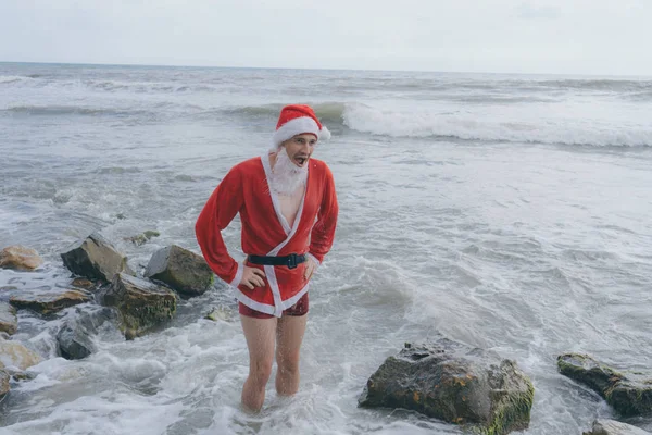 年轻和瘦的圣诞老人在海边度假 圣诞节休息的概念 新年快乐 圣诞愉快 — 图库照片