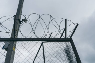 Bir çit dikenli tel, gri gökyüzü fon askeri bir tesis ile