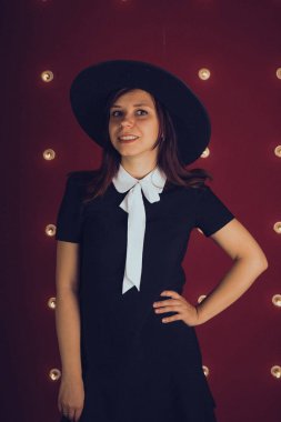 Kız siyah elbise ve siyah şapka kırmızı zemin üzerine poz