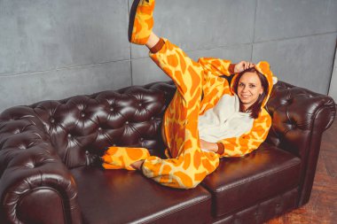 Pijama bir kanguru şeklinde. duygusal portre bir öğrencinin arka plan deri kanepede. Takım elbiseli çılgın ve komik kız. Çocuk partilerine için animatör