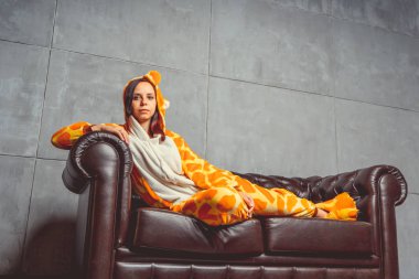 Pijama bir kanguru şeklinde. duygusal portre bir öğrencinin arka plan deri kanepede. Takım elbiseli çılgın ve komik kız. Çocuk partilerine için animatör