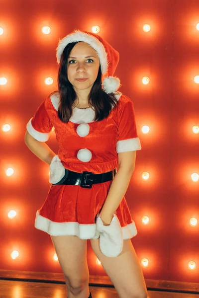 パーティー お祝い クリスマスと新年 サンタ クロースの赤い帽子を身に着けている美しい少女 赤の背景に官能的なクリスマスの女の子 セクシーなサンタのヘルパーの女の子 新しい年 クリスマスの時期 クリスマスのお祝い — ストック写真