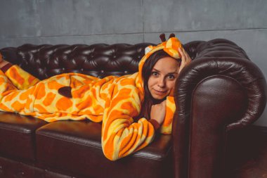 Pijama bir zürafa şeklinde. Duygusal portre bir öğrencinin arka plan deri kanepede. Takım elbiseli çılgın ve komik adam.