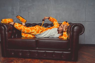 Pijama bir zürafa şeklinde. Duygusal portre bir öğrencinin arka plan deri kanepede. Takım elbiseli çılgın ve komik adam.