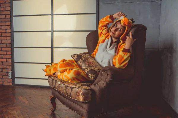 キリンの形でパジャマ 背景の革ソファの上学生の感情的な肖像画 スーツを着たクレイジーで面白い男 — ストック写真