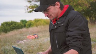 Bir dizüstü bilgisayar açık havada kullanma yakışıklı delikanlı. Öğrenci hoş bir atmosfer açık havada içinde laptop ile studyin üzerinde duruldu. Teknoloji, iletişim, eğitim ve uzak çalışma kavramı