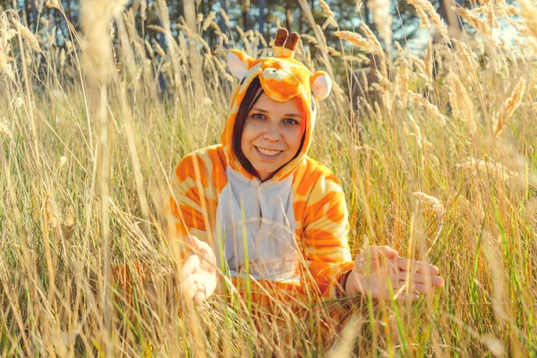 女の子の笑顔 面白いキリンジグソー衣装 小麦畑に座っているパジャマで感情的な学生 子供達のパーティーの概念アニメーター — ストック写真
