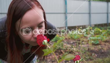 Güzel bir kadın portresi Park'taki gül ün burnunu çekmek. Yakın çekim yüz ve gül. Yan görünüm.