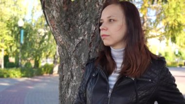 Dalgın kız ile smartphone Şehir Parkı içinde elinde. kadın yeşil ağaçlar çerçevede cep telefonu ekran bakıyor. Kız haber smartphone--dan okur.