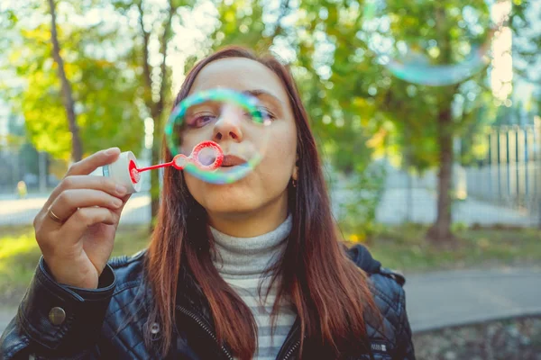Woman blowing soap bubbles outdoor. Teen girl having fun in the park - blowing soap bubbles