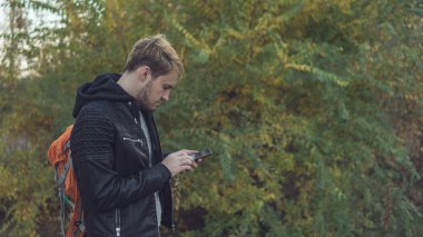 Caddedeki deri ceketli adam, akıllı telefondan mesaj yazıyor. Telefonu olan adam.