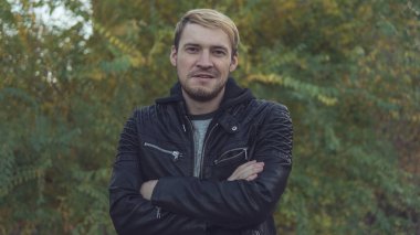 Sonbahar doğaya karşı poz yakışıklı bir adam. Sokakta bir deri ceketli sarışın