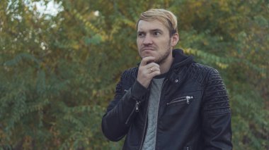 Sonbahar doğaya karşı poz yakışıklı bir adam. Sokakta bir deri ceketli sarışın