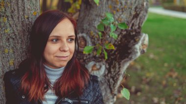 Bir ağacın yanında poz güzel genç kız